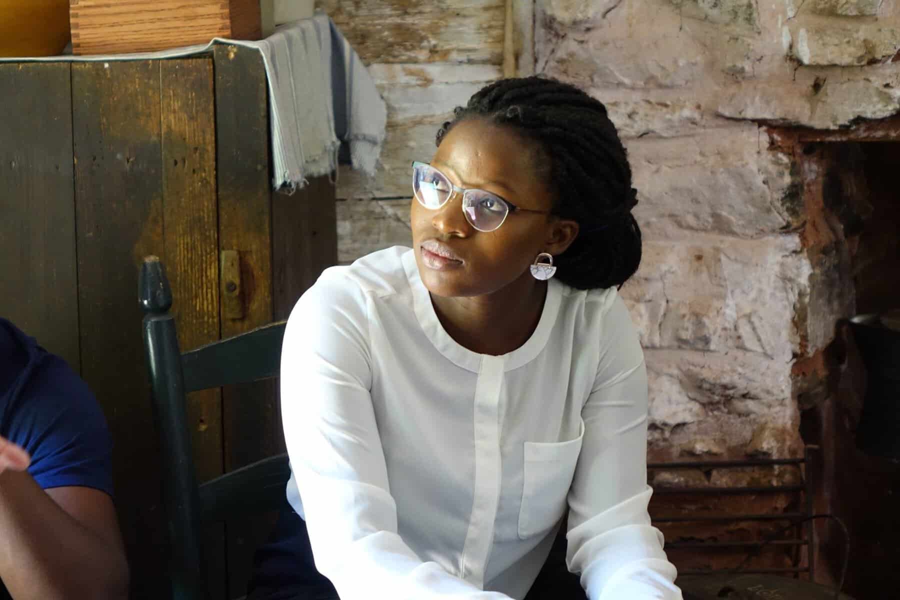 An African American woman sits in the cabin of the enslaved residents of James Madison's Montpelier