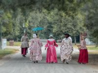 Women walk down a road in historical period dress in Colonial Williamsburg